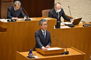 市議会において市長が壇上で話しているところ